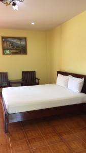 uma grande cama branca num quarto com duas cadeiras em Poon Suk Hotel Kabin Buri em Kabin Buri