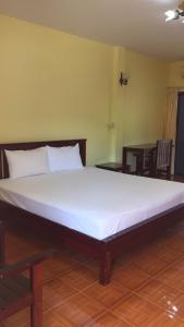 Cama blanca grande en habitación con suelo de madera en Poon Suk Hotel Kabin Buri, en Kabin Buri