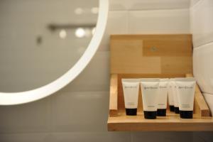 a row of four cups on a wooden shelf in a bathroom at Candy's Boutique Rooms in Asprovalta