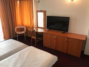 a hotel room with a television and a desk with a bed at Pensiunea Tempo Sovata in Sovata