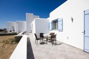 Sahas Apartments في مدينة ميكونوس: منزل أبيض مع طاولة وكراسي على الفناء