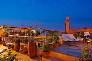 eine Dachterrasse mit Stühlen und einem Uhrturm in der Unterkunft Riad Cinnamon by Marrakech Riad in Marrakesch