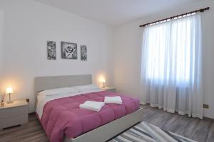 a bedroom with a large bed with a purple blanket at Appartamenti Casa La Rosa in Bellagio