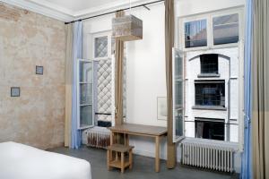 a bedroom with a bed and a table and windows at B&B DRUUM in Brussels