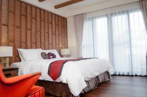 小琉球的住宿－泰美風情旅店，一间卧室配有一张大床和一张红色椅子