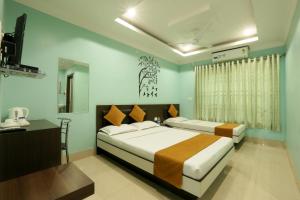 a bedroom with two beds and a desk and a television at Hotel Grand Luit in Guwahati