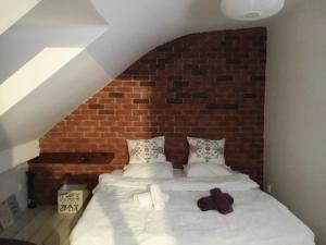 a bedroom with a white bed with a brick wall at Apartment Bonbon 1 in Sarajevo