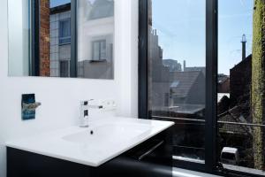 a bathroom with a white sink and a window at B&B DRUUM in Brussels