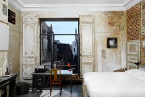 a bedroom with a bed and a desk and a window at B&B DRUUM in Brussels