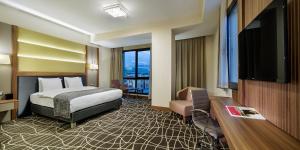 um quarto de hotel com uma cama e uma televisão de ecrã plano em Ramada By Wyndham Elazığ em Elazig
