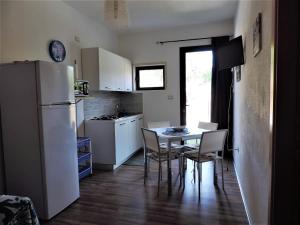 a kitchen with a white refrigerator and a table and chairs at Residenza Belvedere in Orosei