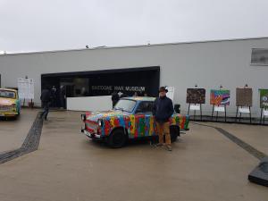 un hombre de pie junto a un coche colorido en un edificio en B&B La Chabetaine, en Morhet