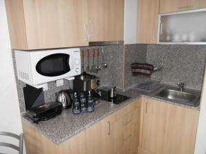 a kitchen counter with a microwave and a sink at Студио D-41 в Апарт-хотел Боровец Гардънс in Borovets