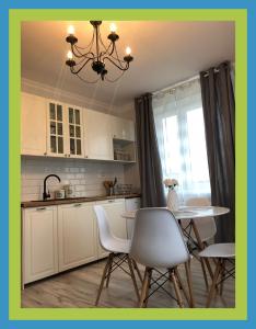 eine Küche mit einem Tisch, Stühlen und einem Kronleuchter in der Unterkunft Apartamenty Zdrojowe in Krasnobród