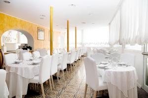 una sala da pranzo con tavoli bianchi e sedie bianche di Hotel Iva a Diano Marina
