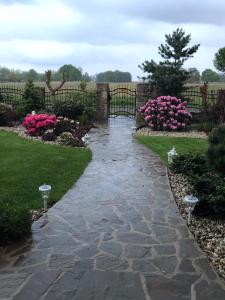 a stone walkway in a garden with pink flowers at Feniks Agro&Spa Adults Only in Świnoujście