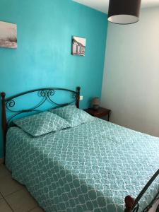 1 dormitorio con 1 cama con pared azul en LILLOT GREEN Appartement en Sanguinet