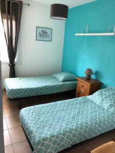 2 camas en una habitación con paredes azules en LILLOT GREEN Appartement en Sanguinet