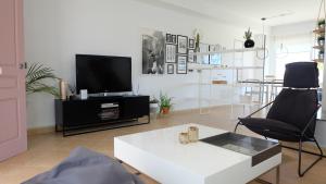 a living room with a tv and a white table at EBLI House in San Miguel de Salinas