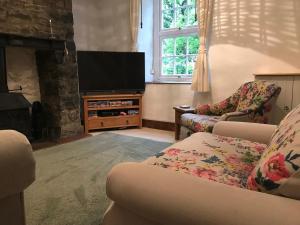 - un salon avec un canapé et une télévision dans l'établissement Riverwash Cottage, à Penmaen-mawr