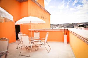 una mesa y sillas en un balcón con sombrilla en Hotel Rincon del Cielo, en San Juan de los Lagos