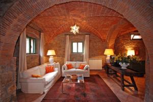 uma sala de estar com um sofá branco e uma parede de tijolos em Fattoria di Casalappi em Campiglia Marittima