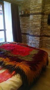 a bed with a colorful blanket on top of it at Family Apartment "Cosy Nature" in Smolyan