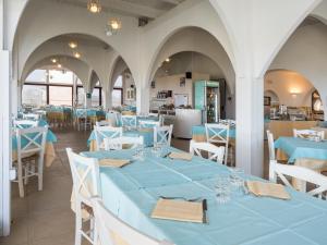 une salle à manger avec des tables bleues et des chaises blanches dans l'établissement Hotel Cala Reale, à Stintino