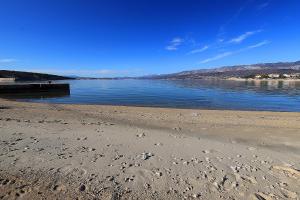 a beach with footprints in the sand and the water at Cool Šilo Appartement Resort in Šilo