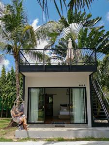 a woman sitting in a hammock in front of a house at Coconut Wells Phuket in Chalong 