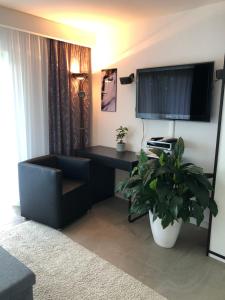 a living room with a desk and a chair and a tv at Ferienwohnung Jolene in Weil am Rhein