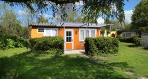 a small yellow and white house with a yard at Bärenklau in Neustadt in Holstein