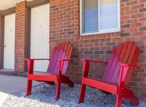 dos sillas rojas y moradas sentadas junto a un edificio de ladrillo en Bear Tracks Inn en Lions Head