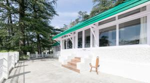 um banco fica do lado de fora de um edifício branco em Glen View Heritage Homestay em Shimla
