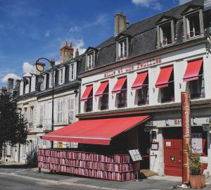 a building with a red awning on a street at Hôtel Mille et une Feuilles in La Charité-sur-Loire
