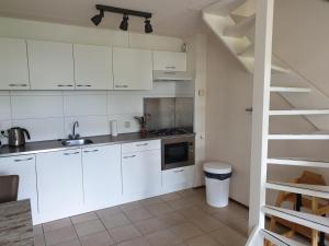a kitchen with white cabinets and a staircase at De Groede in Oosterend