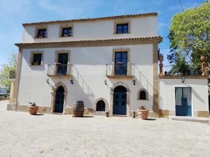 a large white house with blue doors and windows at Casale Di Benedetto in Caltagirone