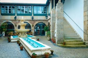 a building with a swimming pool and a fountain at Hotel Fonte da Vila in Monção