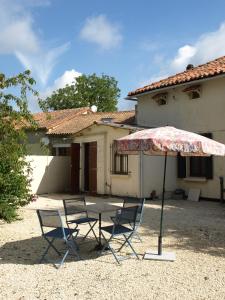 einen Tisch und Stühle sowie einen Regenschirm vor einem Haus in der Unterkunft Gites Le Bois de l'Eglise in Villiers-le-Roux