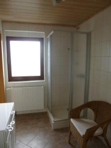 uma casa de banho com um chuveiro, uma cadeira e uma janela. em Jürgen+Carmen Essbüchl em Rodewisch
