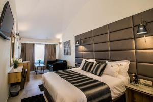 a hotel room with a large bed and a chair at Ask Cozy Rooms in Thessaloniki