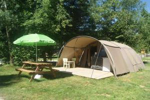 a tent with a picnic table and a green umbrella at Camping Les Arbois in Montjay