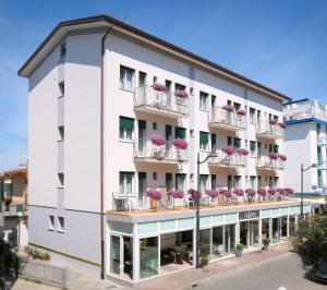 un bâtiment blanc avec des fleurs roses sur les balcons dans l'établissement Hotel Fabris, à Caorle