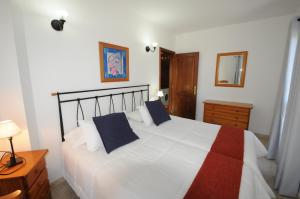 a bedroom with a large white bed with blue pillows at Apartamentos Edalmar in Frontera