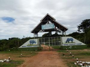 Un edificio con un cartello in mezzo a una strada sterrata. di Rhino Tourist Camp a Ololaimutiek