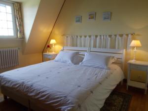 una camera da letto con un letto grande con lenzuola e cuscini bianchi di LES AJONCS a Plougrescant