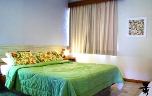 een slaapkamer met een groen bed en een raam bij Pousada Pier do Pontal in Ilhéus