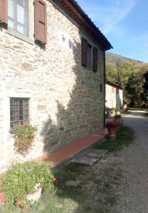 a stone building with a wooden porch on the side of it at apartment details Granaio in Pulicciano