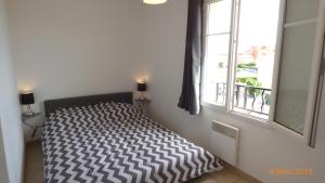 a bedroom with a bed in a room with a window at Grandes Bleues, Appartement T3 duplex, piscine, Narbonne Plage in Narbonne-Plage
