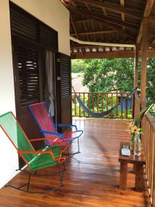 eine Veranda mit Stühlen, einem Tisch und einer Hängematte in der Unterkunft Tortuguero Casa Pelican in Tortuguero